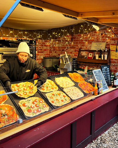 Frisch belegter Flammkuchen wird aus dem Ofen genommen